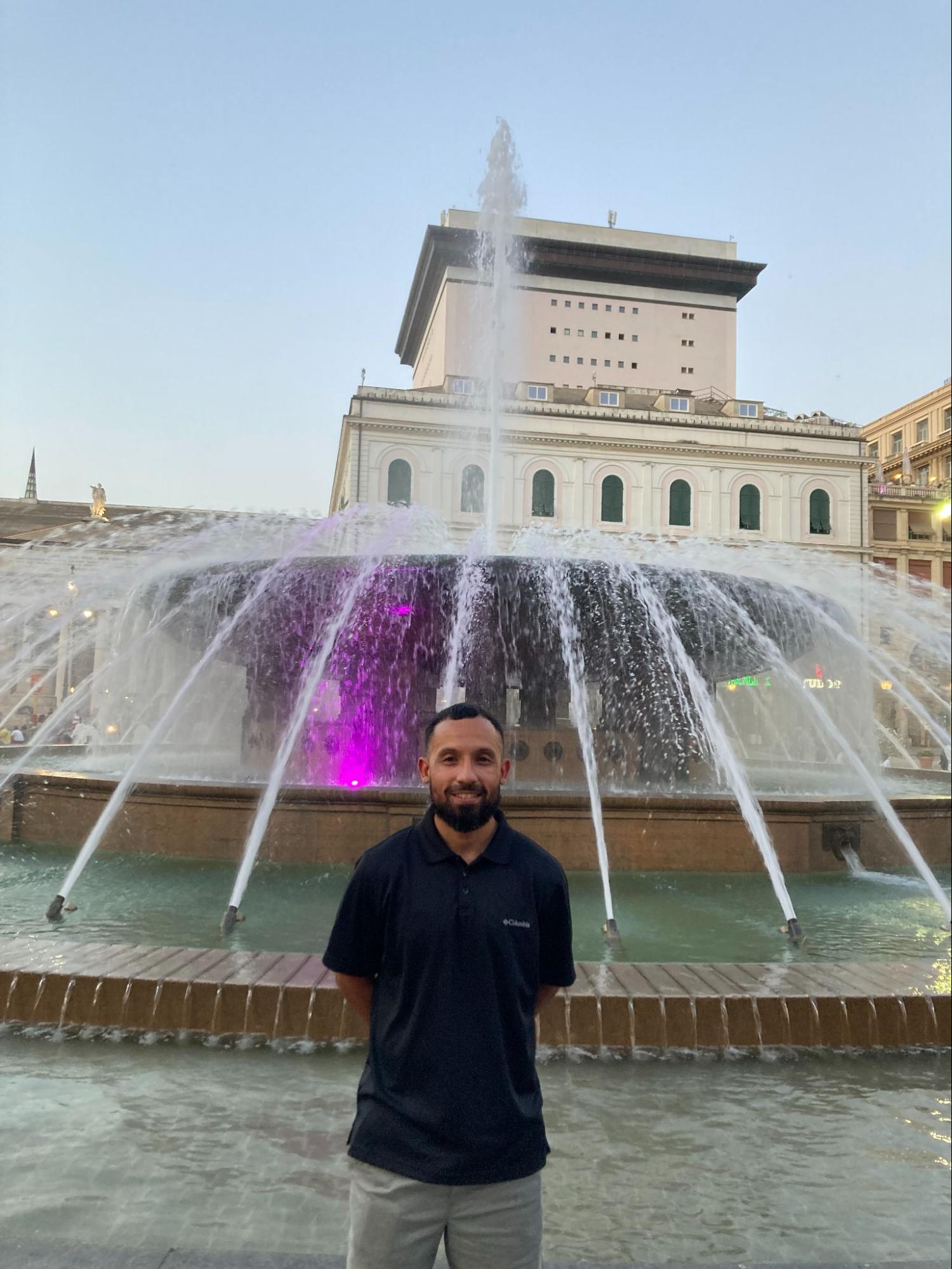 Byron stands in front of a fountain in Italy.