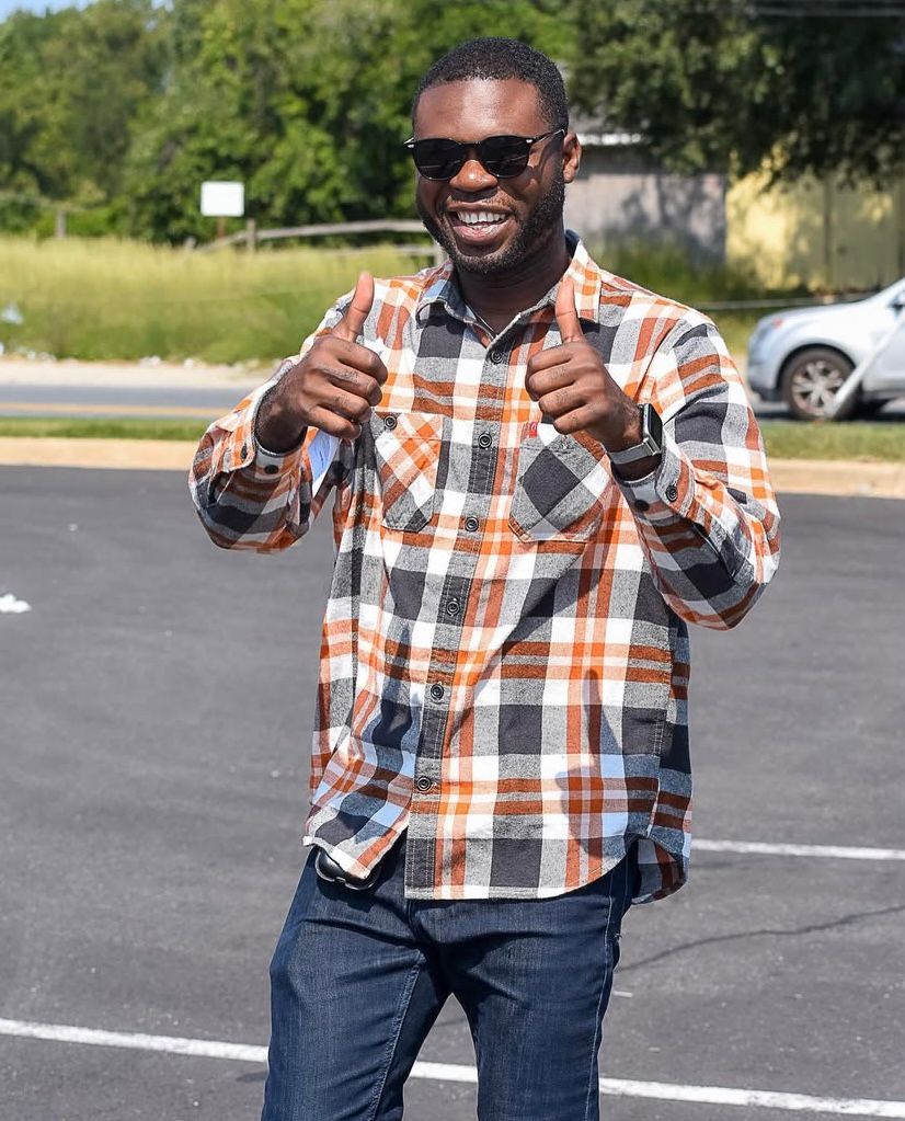 Wearing sunglasses, Victor gives the thumbs up as he smiles.