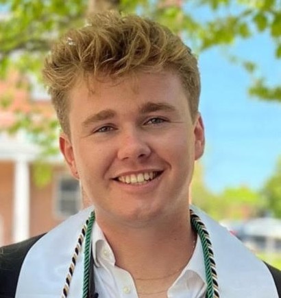 Colin Harnett smiles wearing his graduation robe.