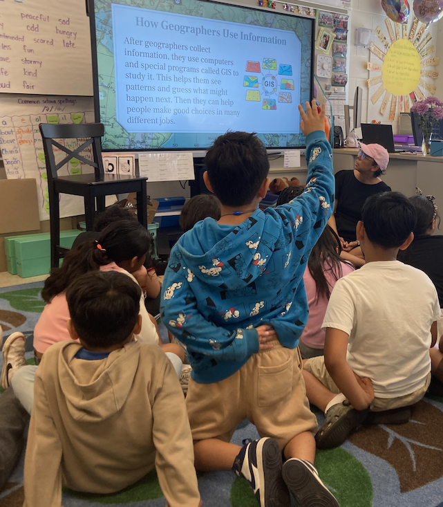 Geographer presents a slideshow about geography to a room of children.