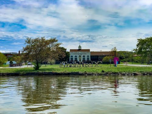 Image shows the Anacostia River in the foreground, a #TrashFreeDC sculpture made of trash and SW DC