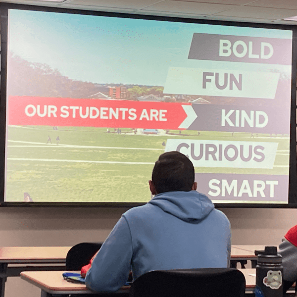 Student look at slide that says "Our students are bold, fun, kind, curious and smart."