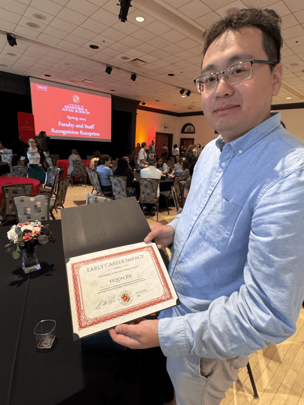 Yiqun Xie displays a certificate for the Early Career Impact Award at the ceremony.
