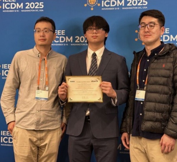 Two men and a young men pose together holding a certificate.