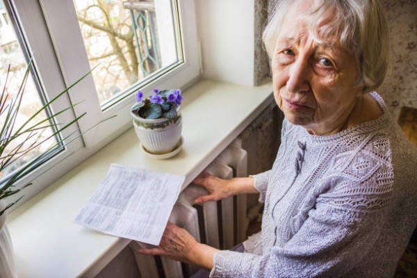 Old woman sitting in front of a heater 