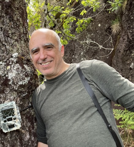 Henrique Pereira smiles as he leans next to a tree