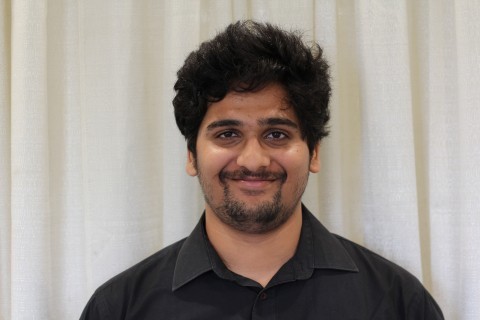 Abhishek dressed in a black shirt smiles at the camera,
