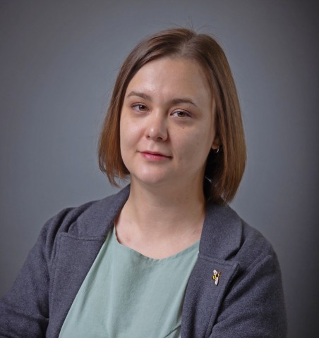 A woman with short hair wearing a green shirt, smiling and looking towards the camera.