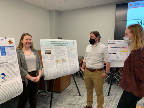 MS students smile in front of their posters at the capstone symposium 