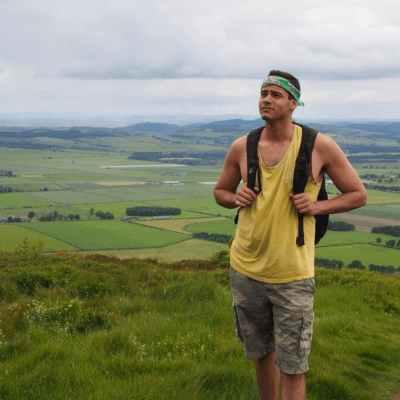 Taylor Oshan wearing a backpack with a hilly landscape as the background