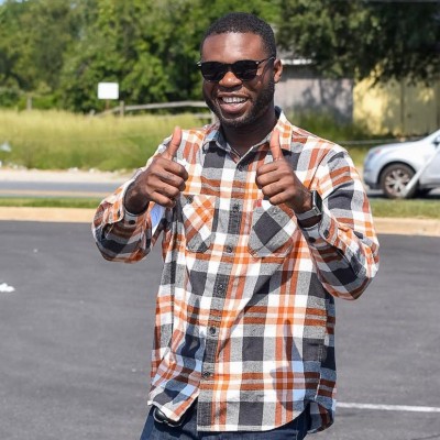 Wearing sunglasses, Victor gives the thumbs up as he smiles.