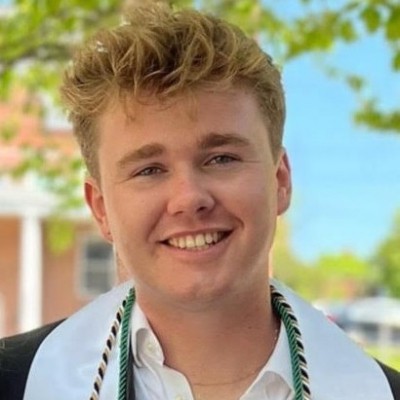 Colin Harnett smiles wearing his graduation robe.